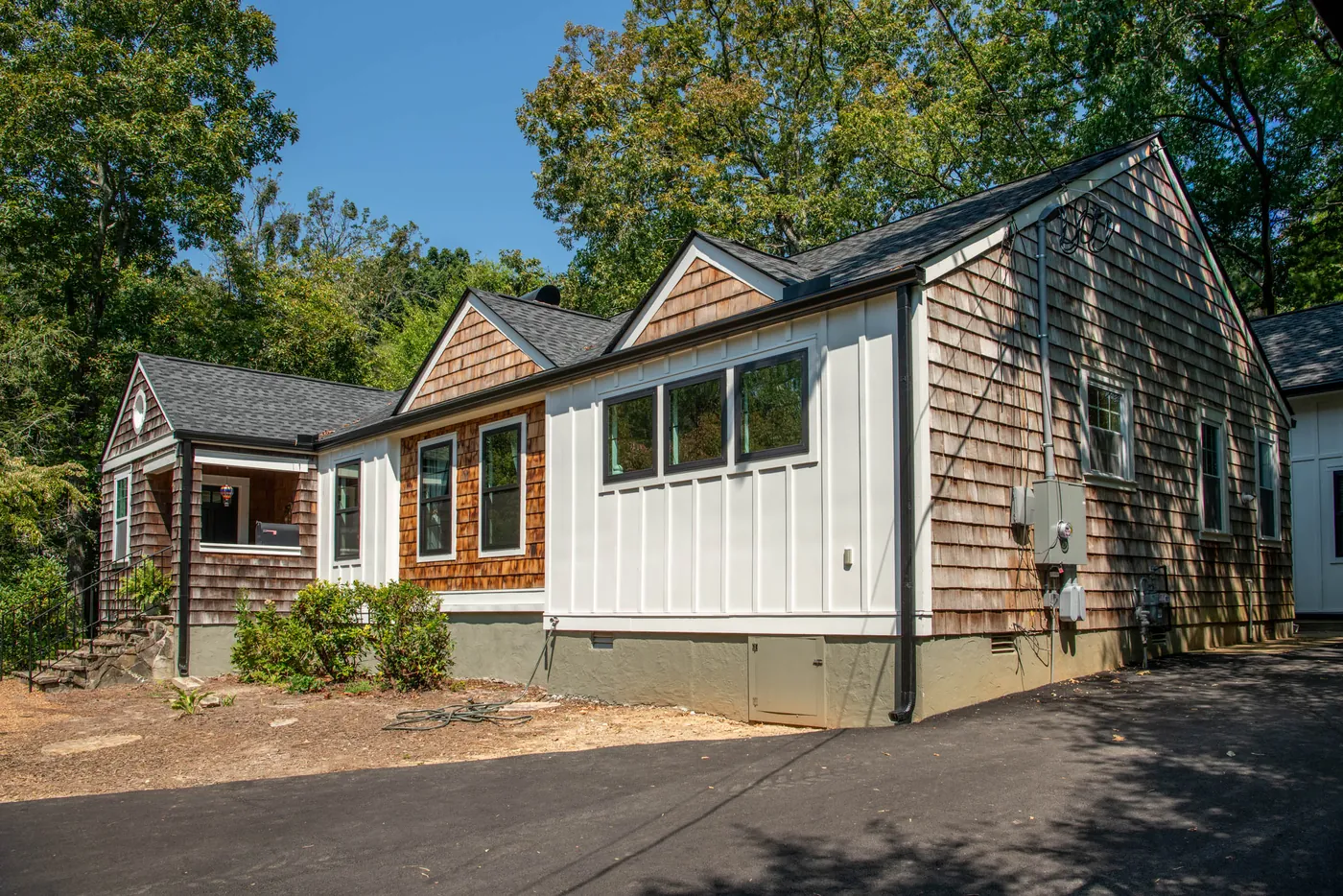 The renovated exterior from the driveway, board-and-batten meeting the original cedar shake