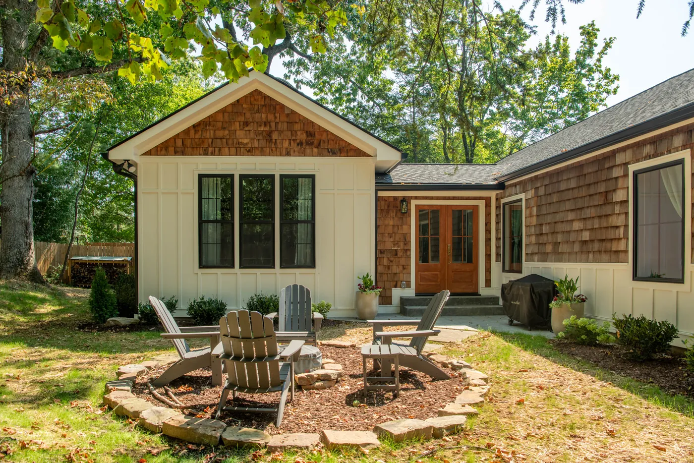 Completed home addition with board-and-batten siding, a cedar shake gable and french doors opening onto a fire pit patio, built by Riverside Construction Services