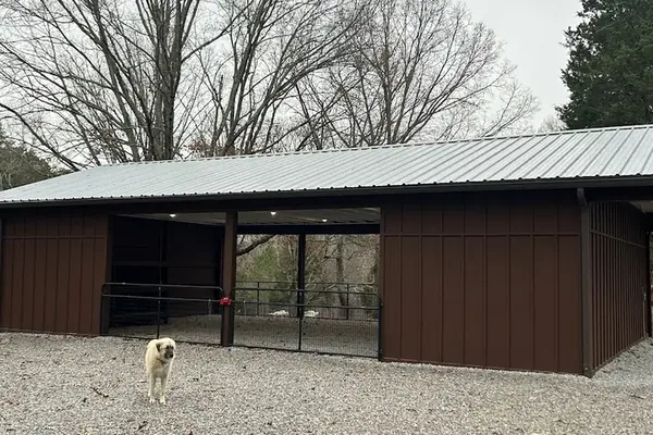 The same barn from an angle, showing the full run of bays and the gravel apron