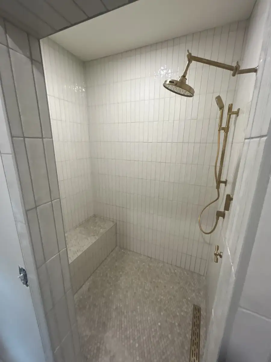 Walk-in tile shower with brass fixtures inside the addition