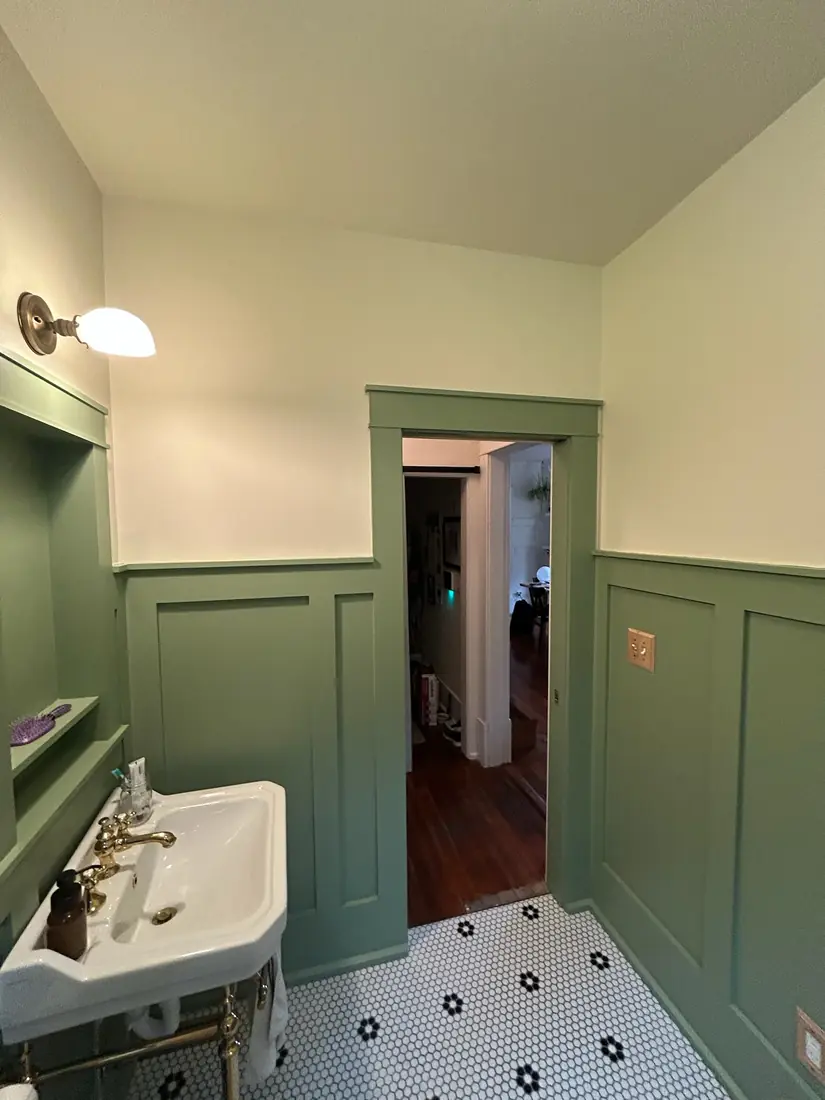 Green craftsman bath with console sink, brass fixtures and pocket door