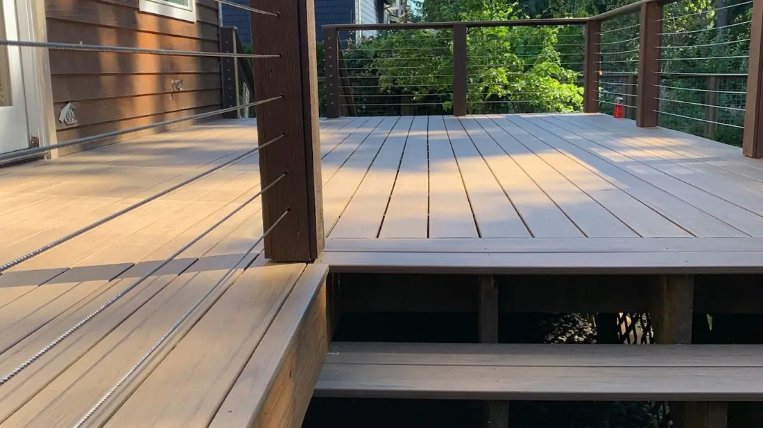 Composite deck with black cable railing overlooking a wooded lot