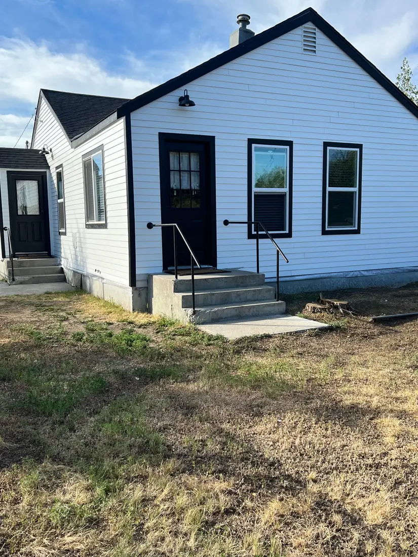 Completed exterior renovation with white siding and black trim