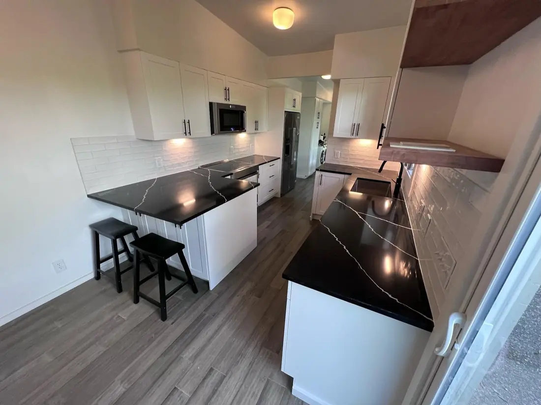 Kitchen with white shaker cabinets and black quartz counters