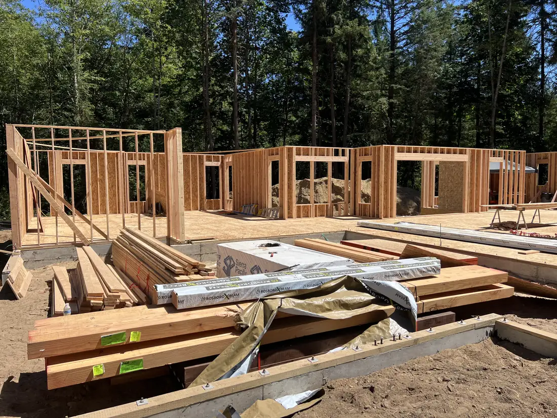 Exterior walls standing with framing lumber staged on the deck