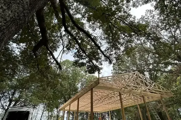 Truss frame standing beneath a mature oak before the roof went on
